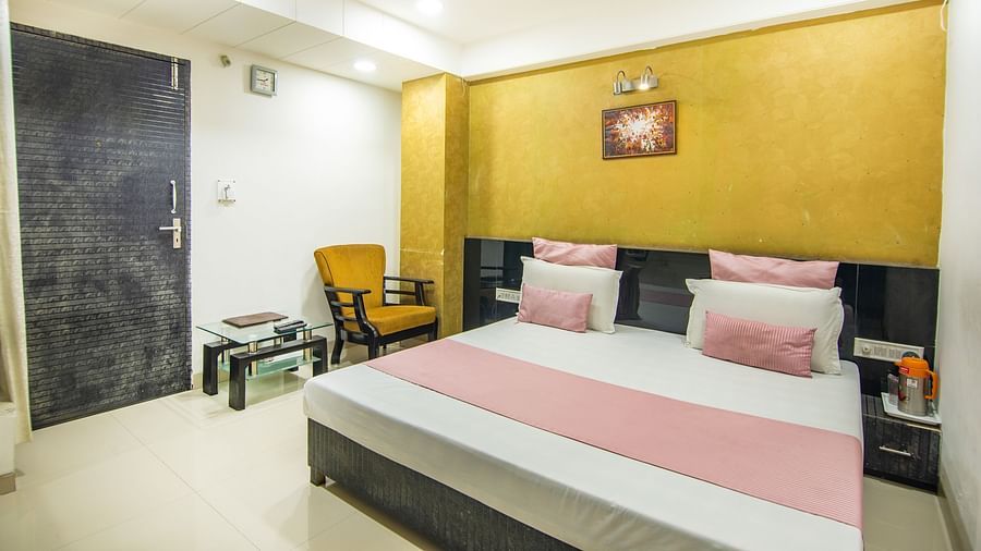 A room featuring a well-made bed, a coffee table, a side drawer, and a sofa chair