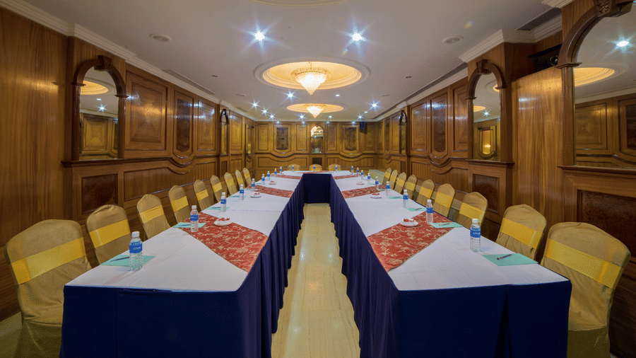 A seating area at a conference hall at Raj Park Hotel in Chennai, with chandeliers, chairs, and tables set up for an event.