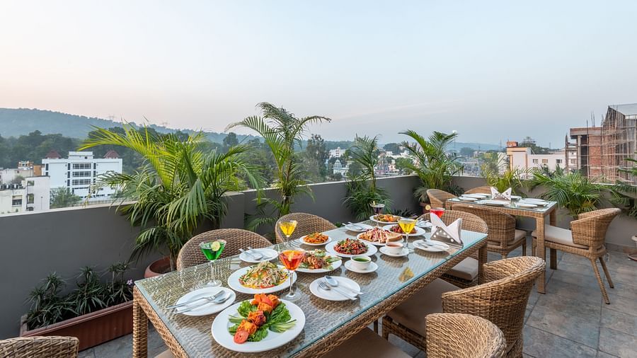 The dining area at the terrace top set up with chairs and tables overlooking the city view - DLS Hotel Arihant, Haridwar