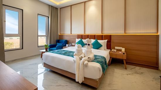 a double bed with blue runner and side tables inside one of the Rooms - The Orchid Hotel, Jamnagar