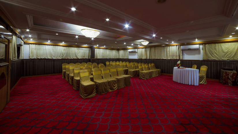 A seating arrangements inside the Senate Banquet hall at the Raj Park Hotel in Chennai, featuring chairs, lights, and a table  witha few chairs.