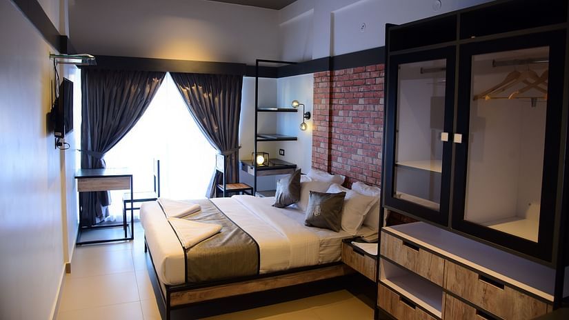 a double bed with a tv opposite it inside one of the rooms - VITS Select Mangalore 