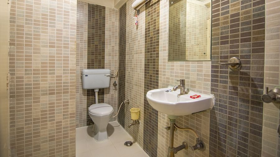 A washroom featuring a large mirror, a sink and a western toilet - Hotel Morya, Bhopal