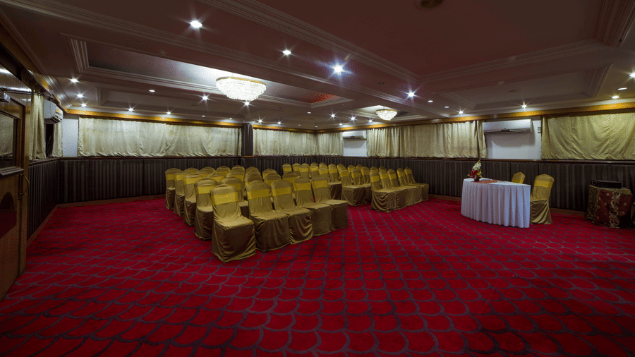 A seating arrangements inside the Senate Banquet hall at the Raj Park Hotel in Chennai, featuring chairs, lights, and a table  witha few chairs.