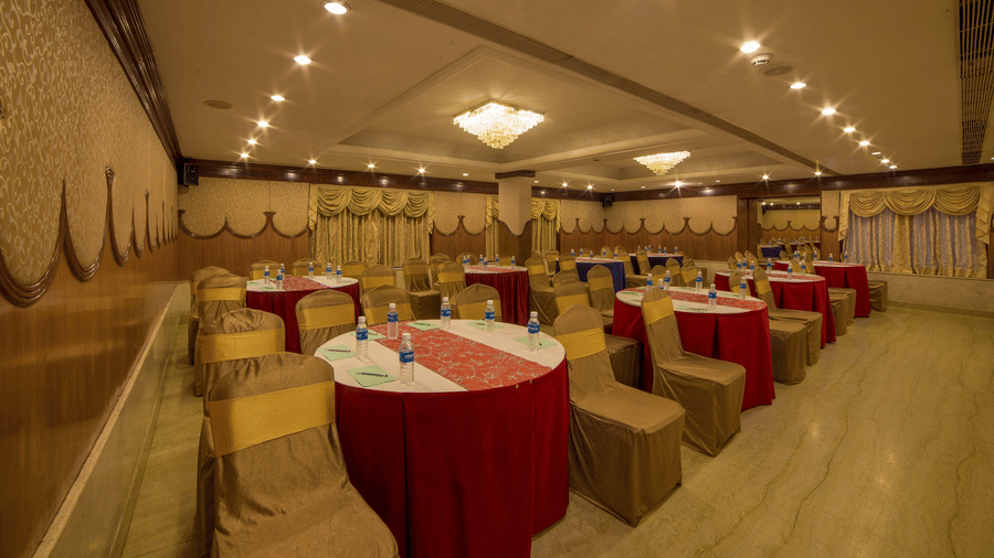 Seating area at Summit conference hall at Raj Park Hotel in Chennai , featuring  chairs, tables, and chandeliers.