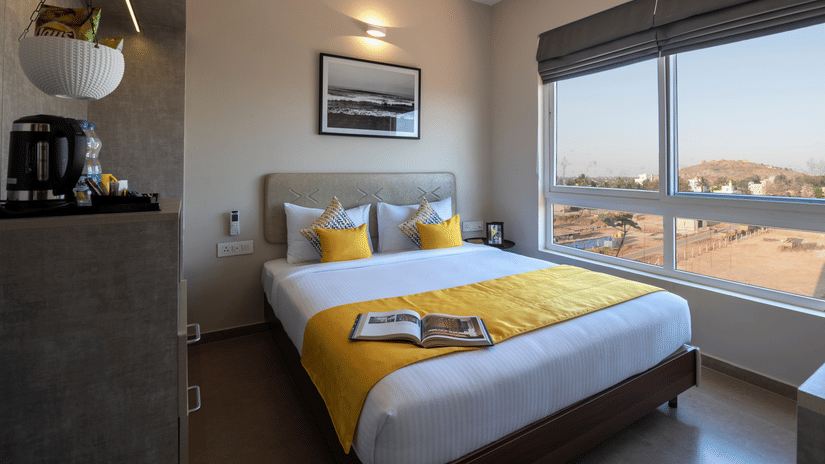 Spacious deluxe room with a large bed, modern interiors, and window view at Avora Tree, a hotel near Bangalore International Airport ideal for comfortable airport stays.