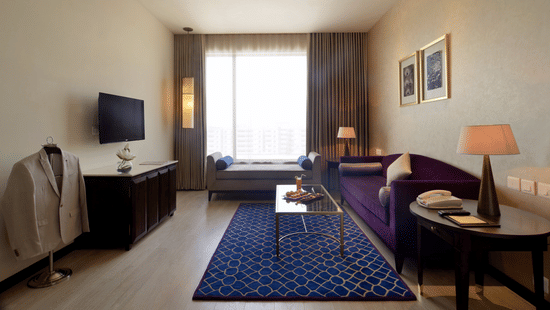 Spacious Premium Room at Marasa Sarovar Premiere, Tirupati with a king size bed, elegant lounge seating, work area, flat screen TV, and modern décor accented by natural light.