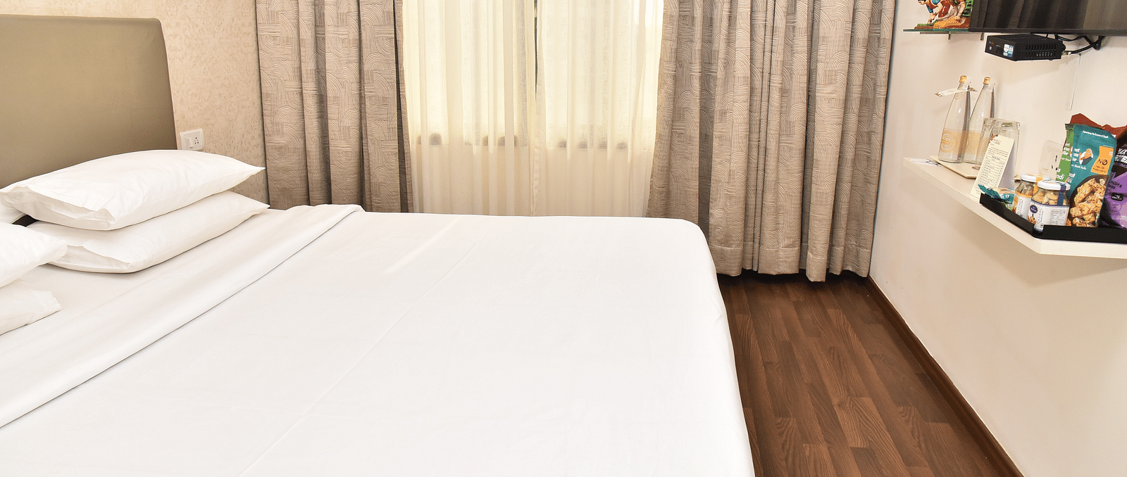 An image of a bedroom in our suite in Kanchipuram, with a large bed positioned in front of a wall-mounted television - Regency Kanchipuram by GRT Hotels