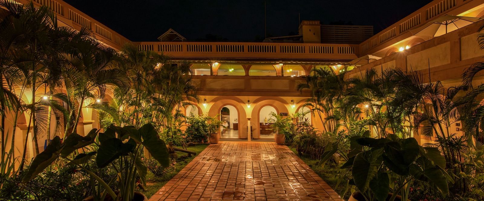 Resort corridor during night time with plants and lights.