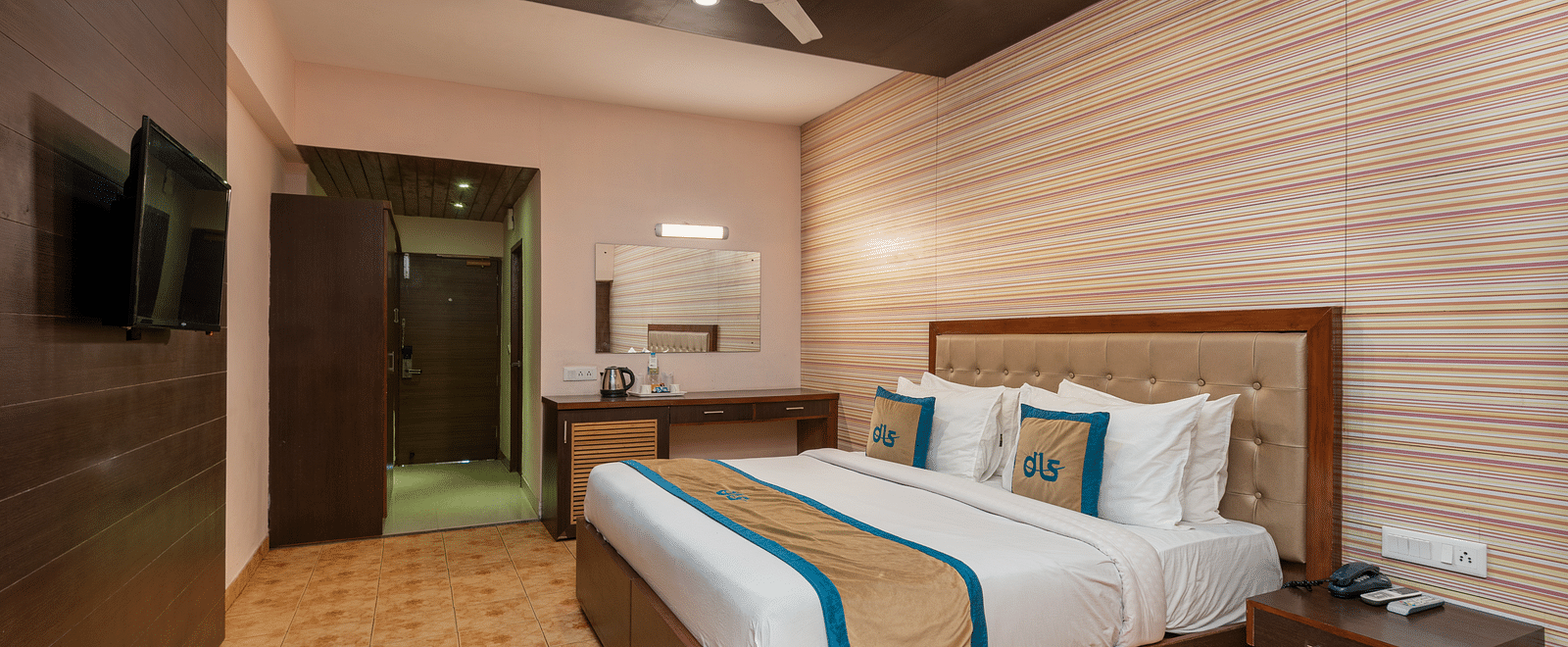 Overview of Deluxe Non view room at DLS Spring Valley resort  Dharamshala featuring a  king bed, table, chairs and a TV