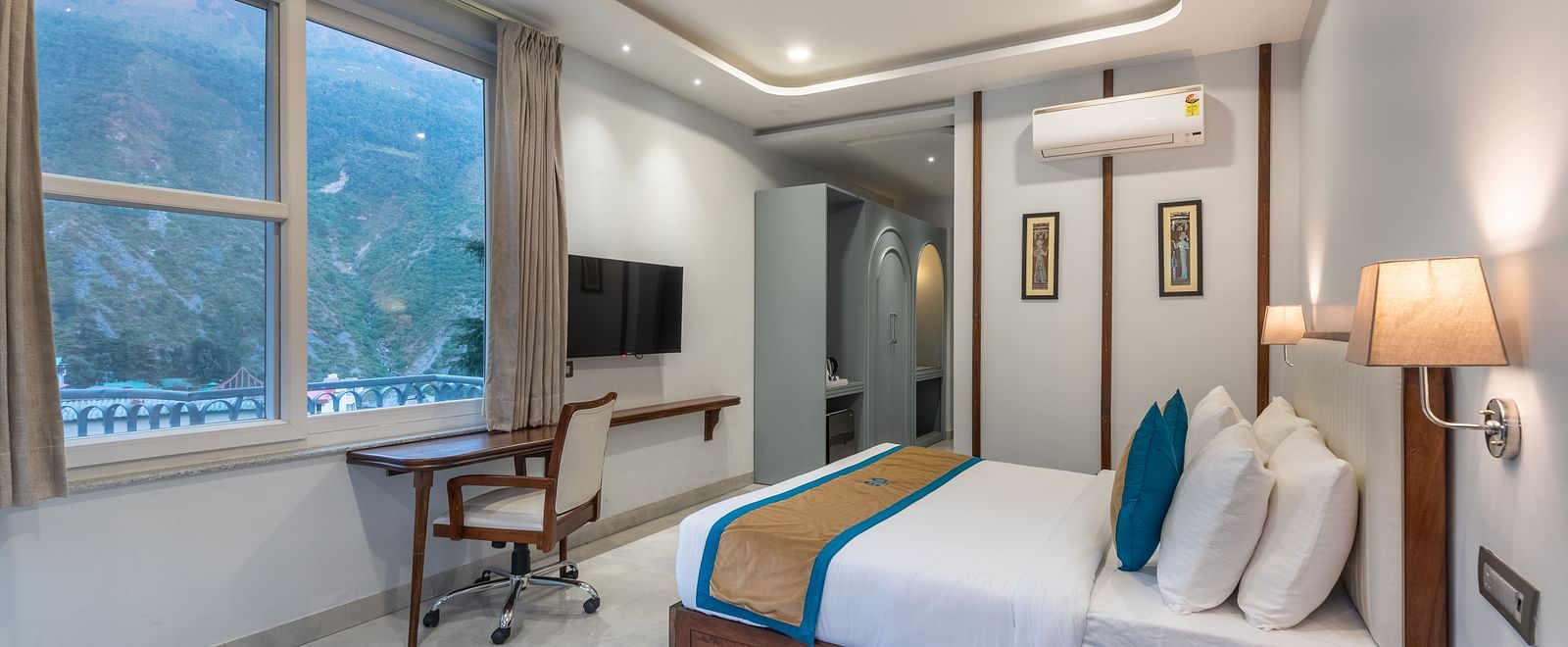 Spring Suite at DLS Spring Valley Resort Dharamshala featuring a kind bed, work desk and chair and ambient lighting from the window