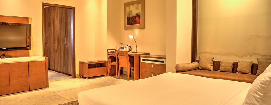 warmly lit bedroom with tv and sofa