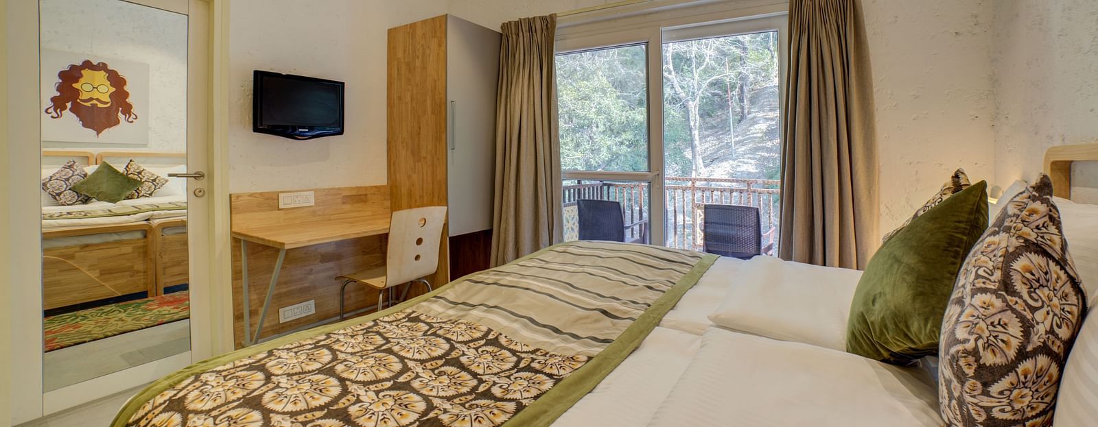 A bedroom with windows opening into the balcony offering forest views and a large bed facing a television - Bedzzz, Rishikesh