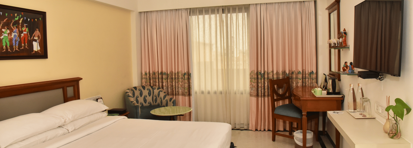 One of our luxury rooms in Kanchipuram featuring a large bed positioned in front of a wall-mounted television - Regency Kanchipuram by GRT Hotels
