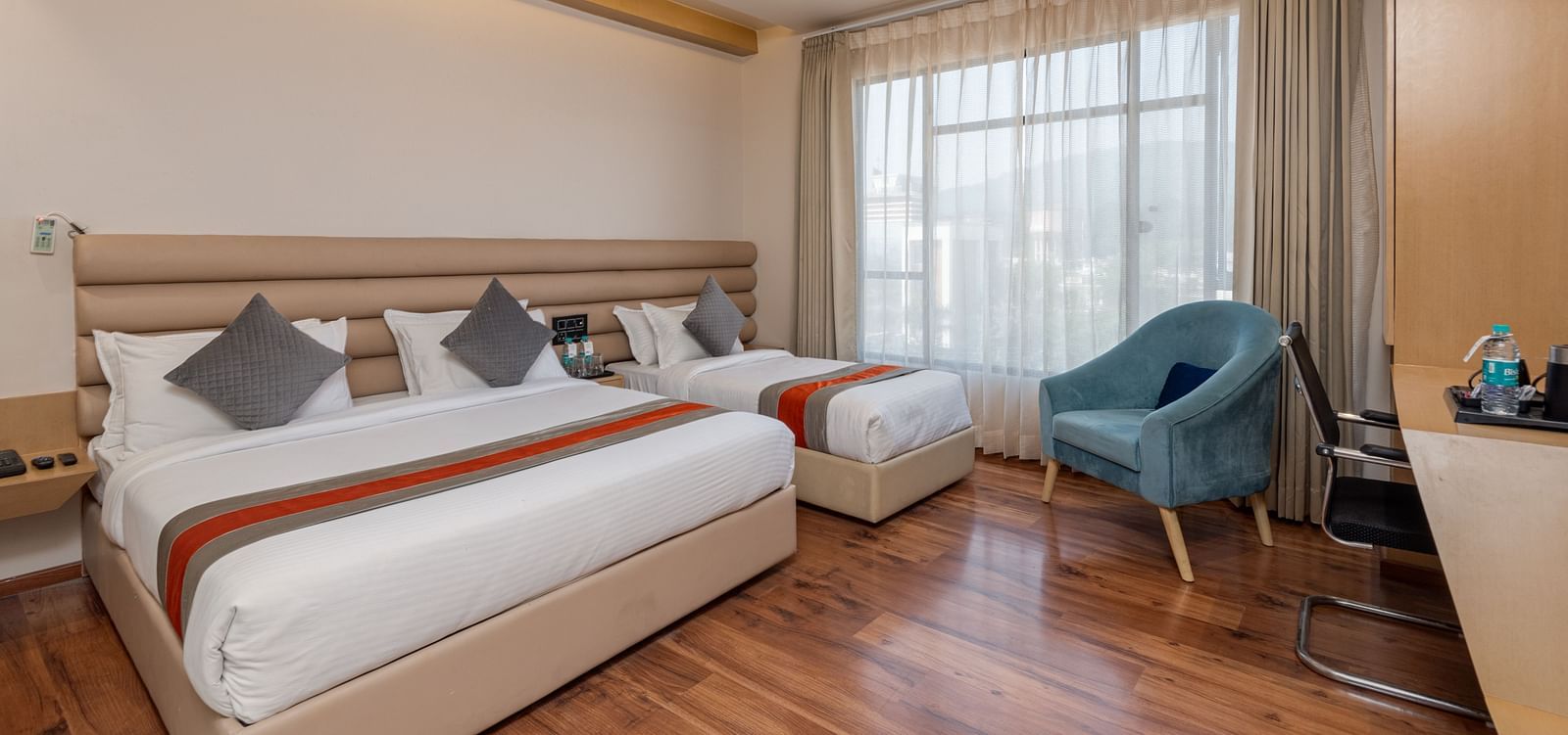 An image featuring a room with two beds, two chairs, a work desk and a window - DLS Hotel Arihant, Haridwar