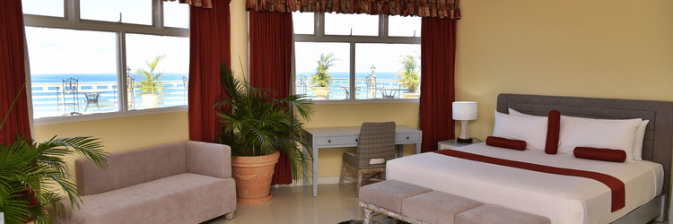 Deluxe Ocean View Room with ocean view windows, featuring a king size bed, a small sofa by the window and a desk at Hotel Grand A View