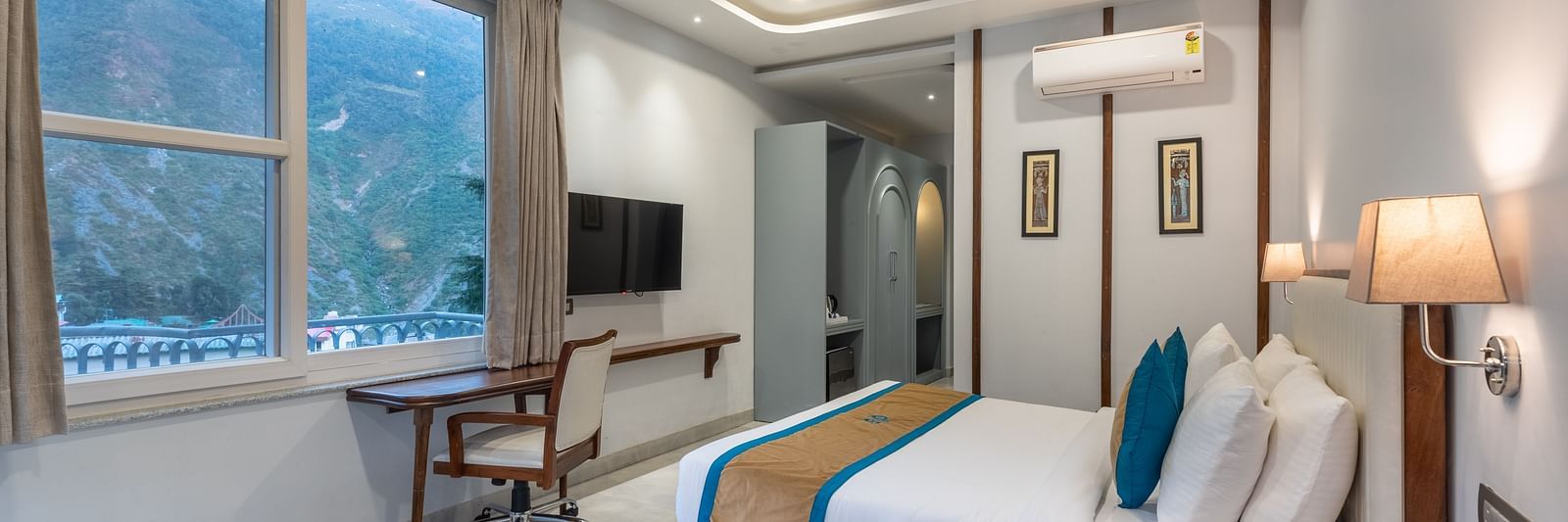 Spring Suite at DLS Spring Valley Resort Dharamshala featuring a kind bed, work desk and chair and ambient lighting from the window