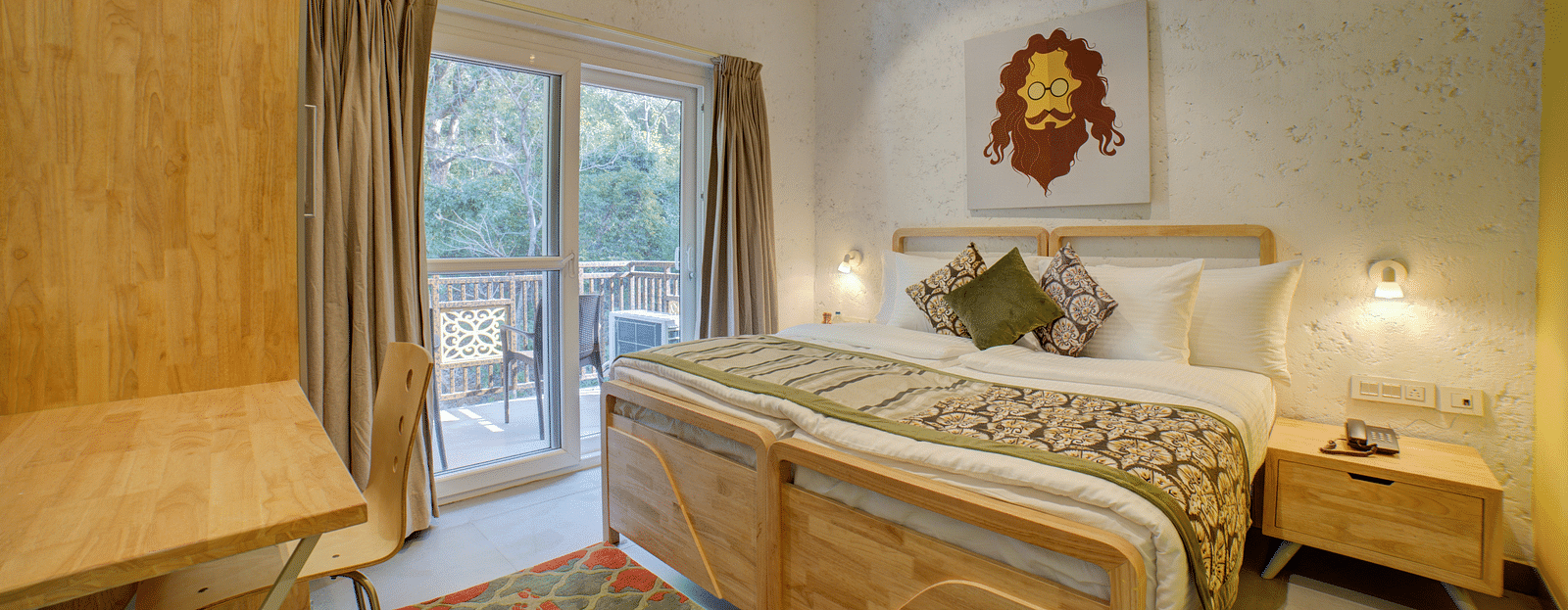 A bedroom with a large bed beside large windows opening into a  balcony with forest views outside - Bedzzz, Rishikesh