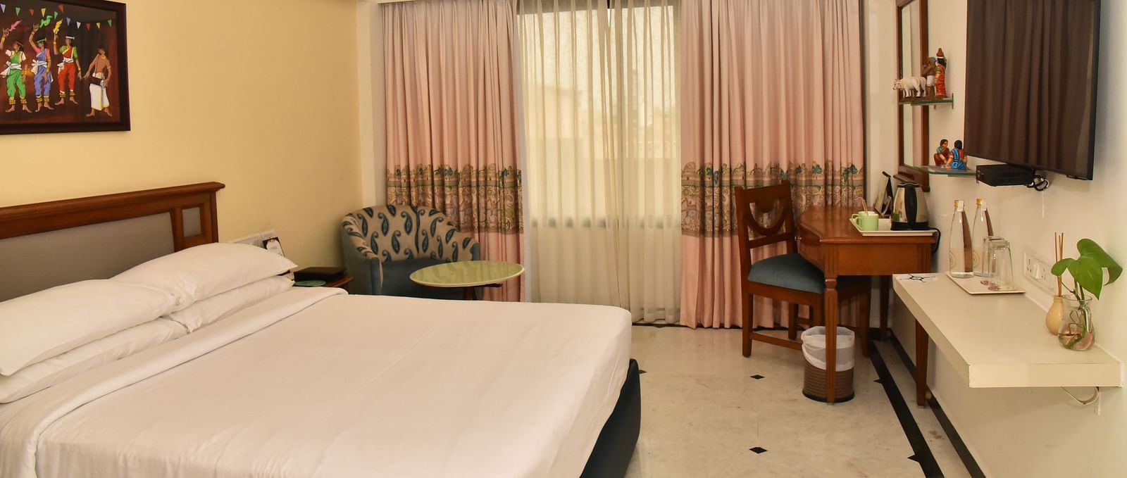 An image of our Deluxe Room featuring a large bed positioned in front of a wall-mounted television - Regency Kanchipuram by GRT Hotels
