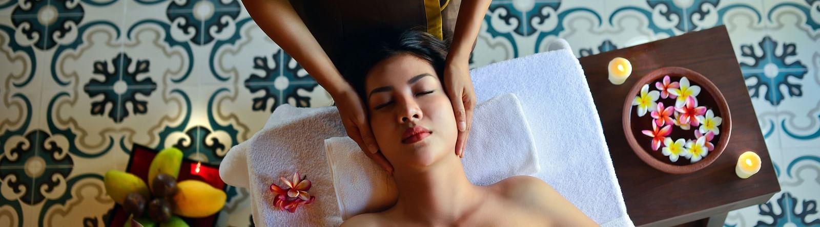 Image of a woman receiving a spa treatment with flowers and fruits on the side