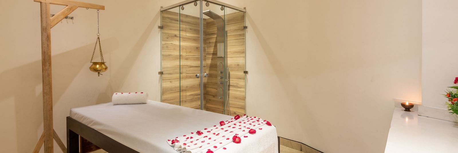 side view of spa with a bed decorated with rose petals and a Shirodhara vessel hanging from a stand at DLS The Classio