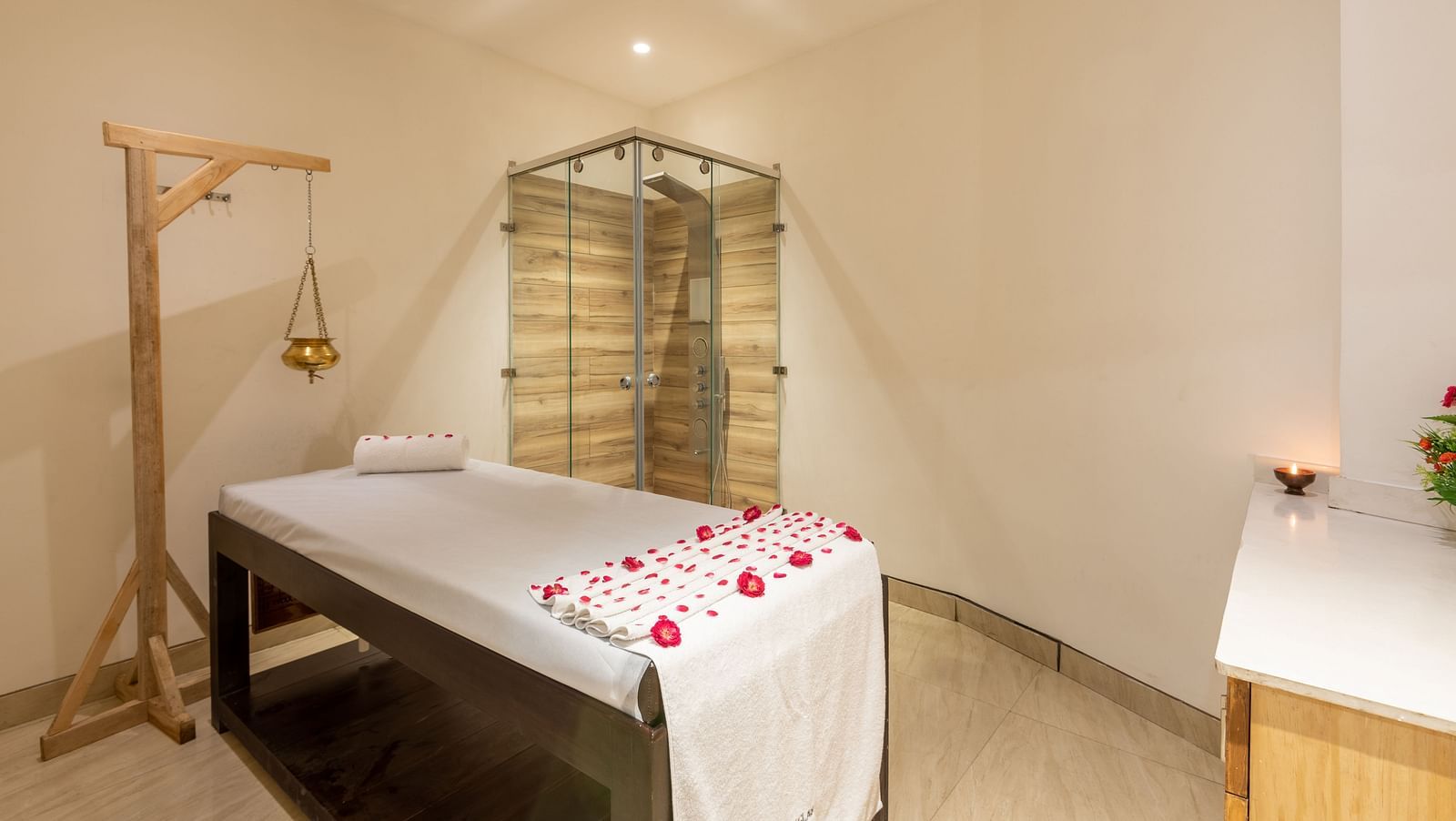 side view of spa with a bed decorated with rose petals and a Shirodhara vessel hanging from a stand at DLS The Classio