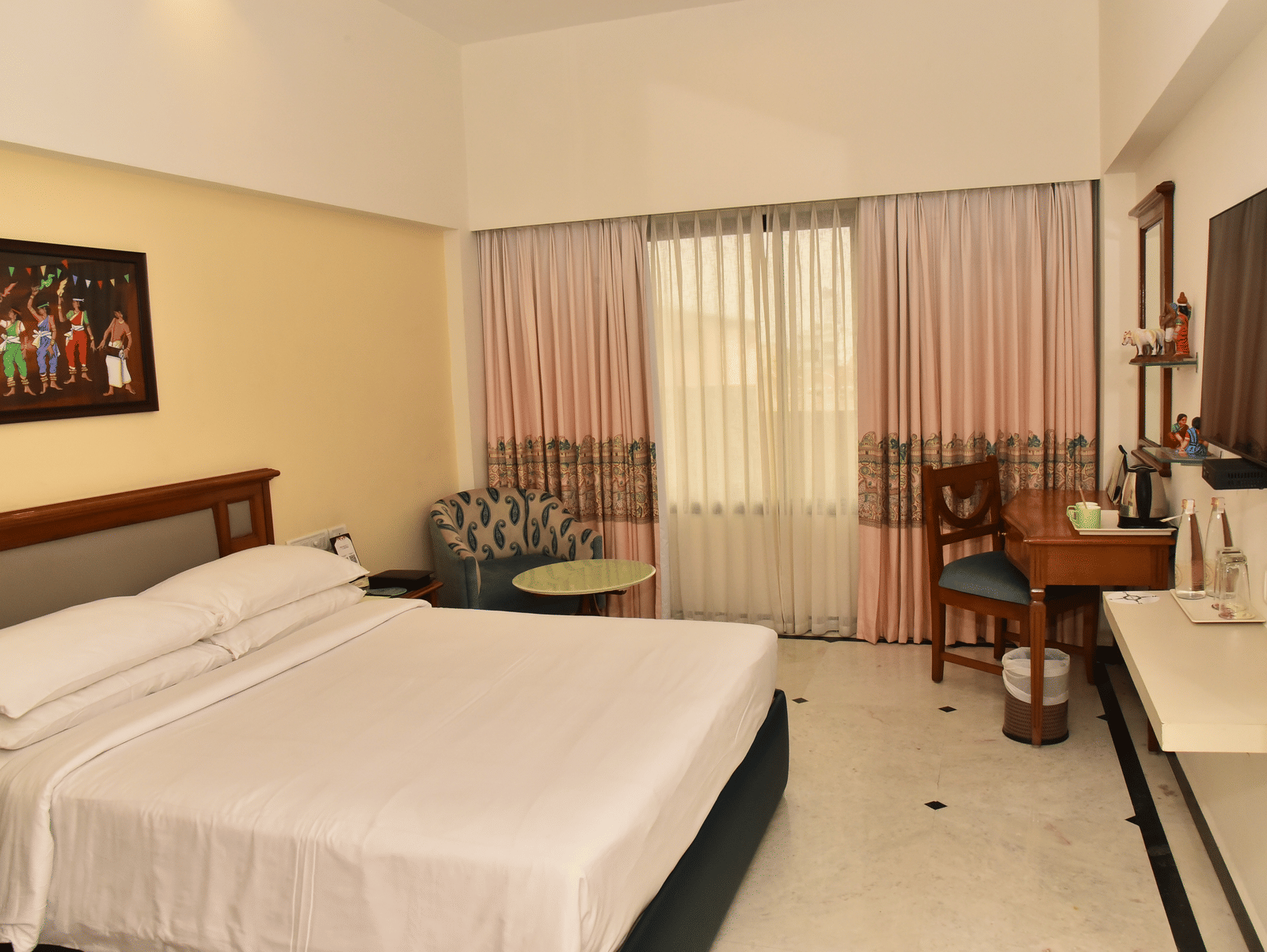 An image of our Deluxe Room featuring a large bed positioned in front of a wall-mounted television - Regency Kanchipuram by GRT Hotels