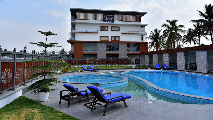 a grand swimming pool in front of resort facade with sunbeds in front and blue sky as the backdrop - Royal Lotus View Resotel