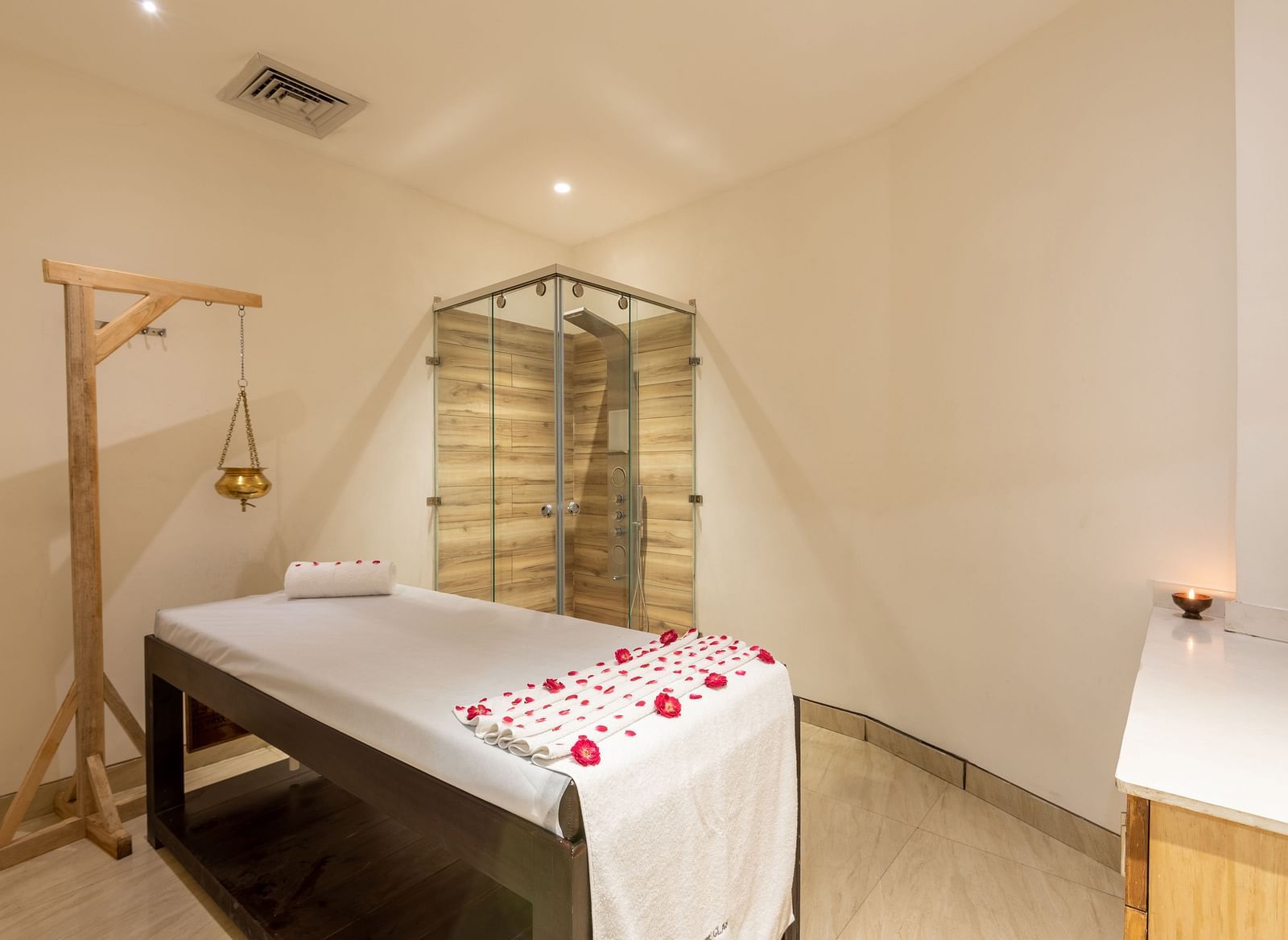 side view of spa with a bed decorated with rose petals and a Shirodhara vessel hanging from a stand at DLS The Classio