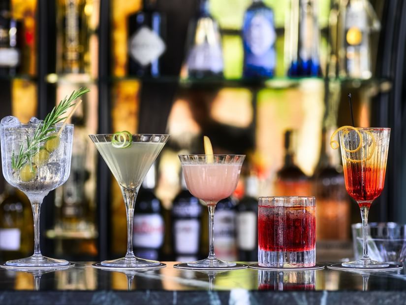 A close up shot of many cocktail drinks placed on the bar counter.