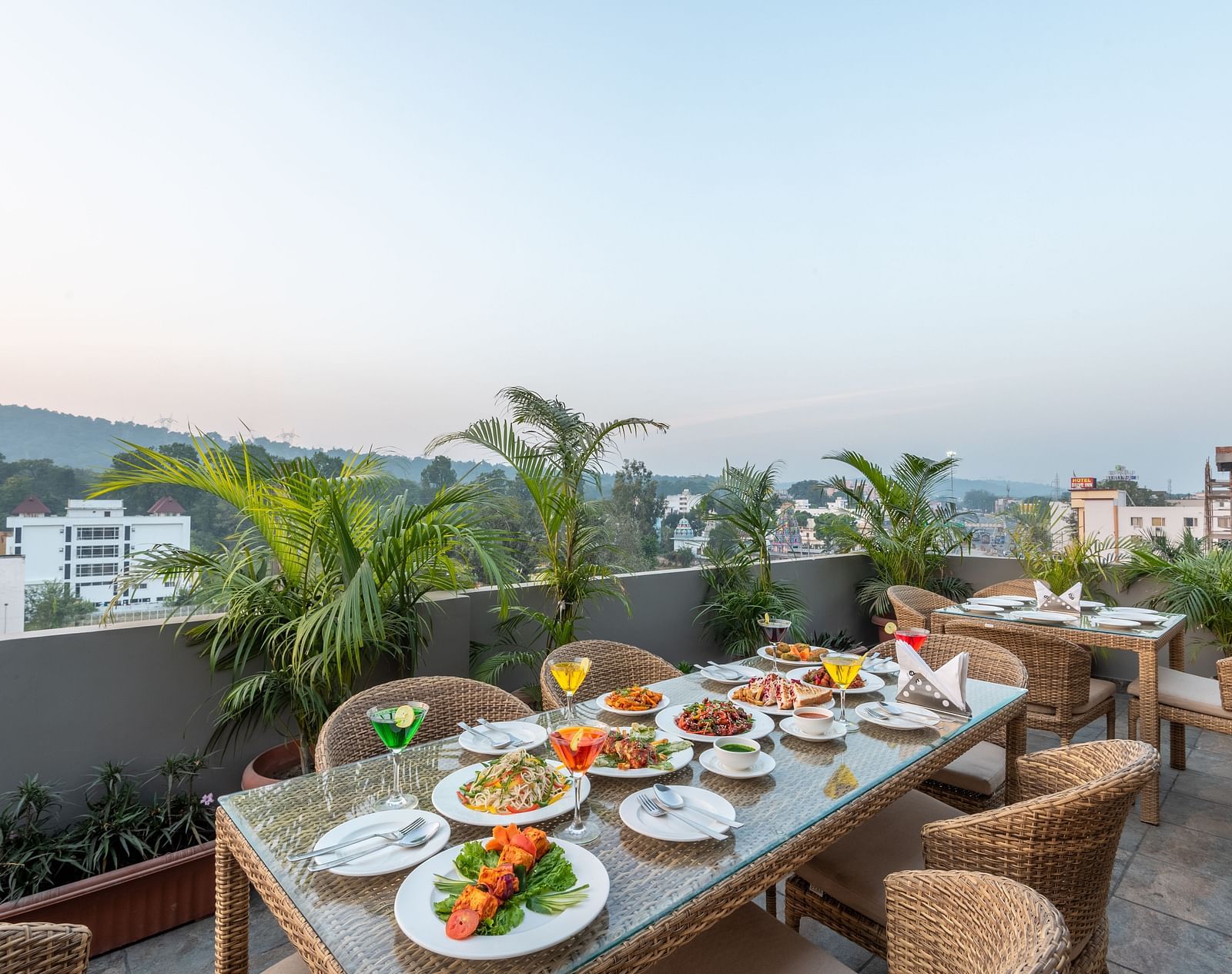 The dining area at the terrace top set up with chairs and tables overlooking the city view - DLS Hotel Arihant, Haridwar