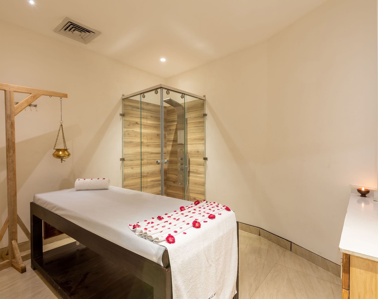 side view of spa with a bed decorated with rose petals and a Shirodhara vessel hanging from a stand at DLS The Classio
