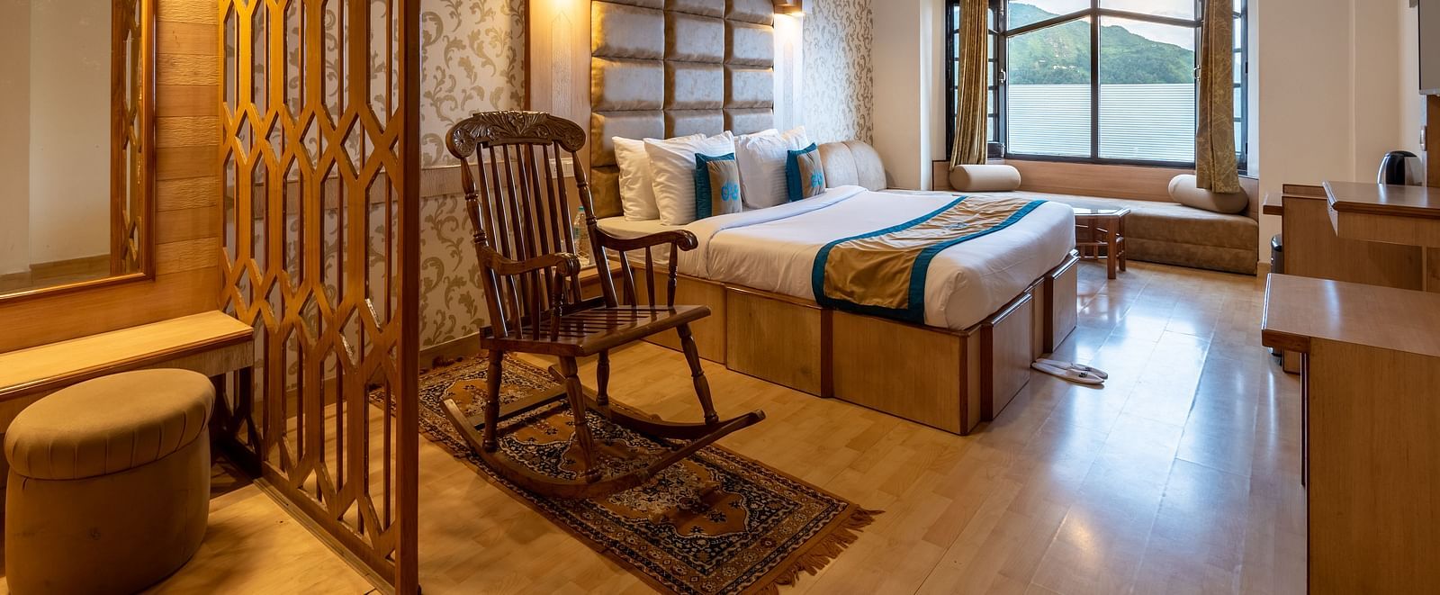 A premium room near Bhagsunag waterfall with elegant wooden decor, a cosy bed, seating area, TV, and stunning mountain views, offering a relaxing ambience - DLS Meghavan Resort, Dharamshala