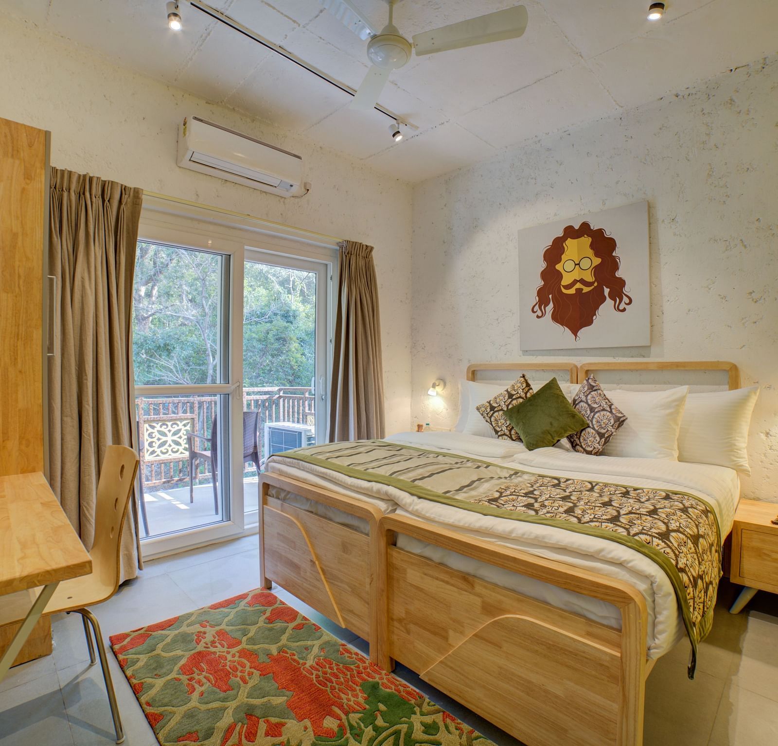A bedroom with a large bed beside large windows opening into a  balcony with forest views outside - Bedzzz, Rishikesh