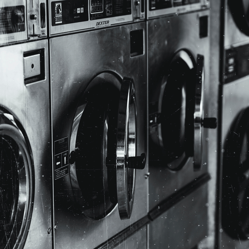 A row of washing machines in a laundromat with a monochromatic colour scheme