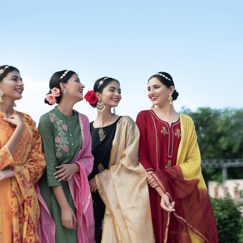 Bridesmaids in colourful traditional outfits enjoying an outdoor wedding celebration.