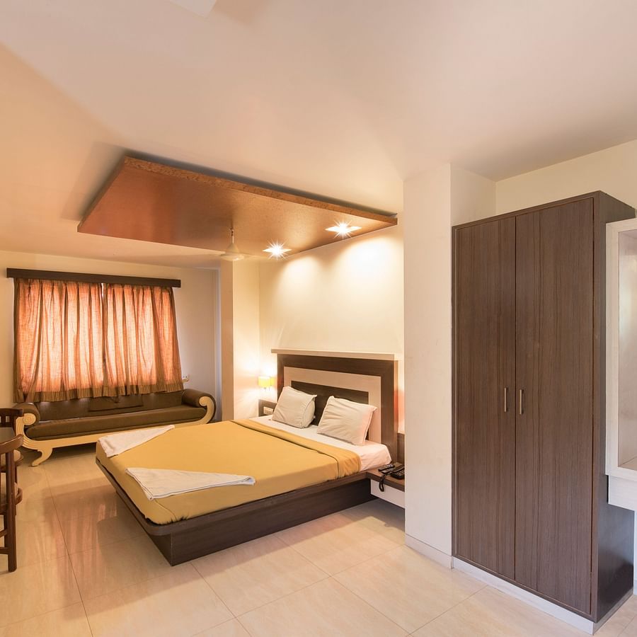 Hotel Vaikunth by Adamo - the bed placed in the bedroom along with a seating area opposite the bed
