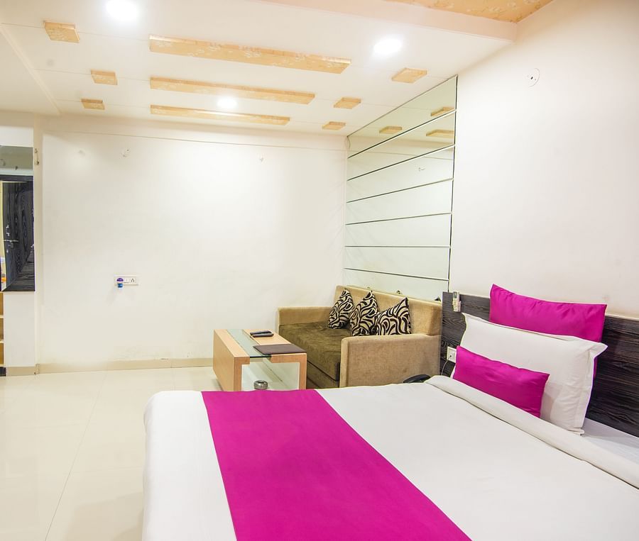 A room featuring a bed, a TV, a coffee table, and a sofa bed - Hotel Morya, Bhopal
