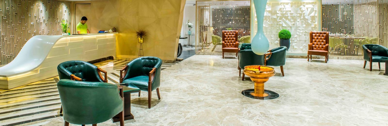 Modern hotel lobby with teal armchairs, a unique light fixture, and a welcoming reception desk | The Citi Residenci Hotel Durgapur