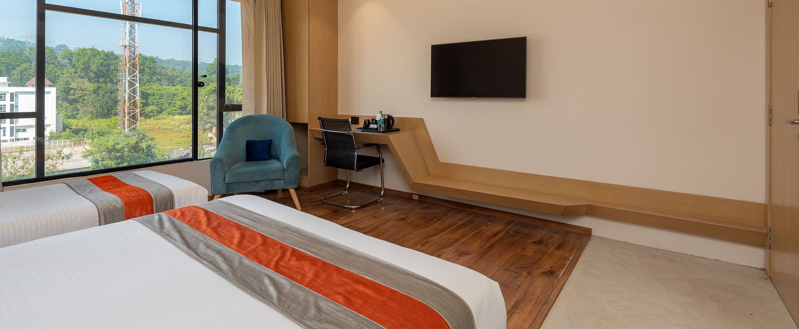 An image of a room with two beds, a work desk, two chairs and an a window overlooking the view - DLS Hotel Arihant, Haridwar