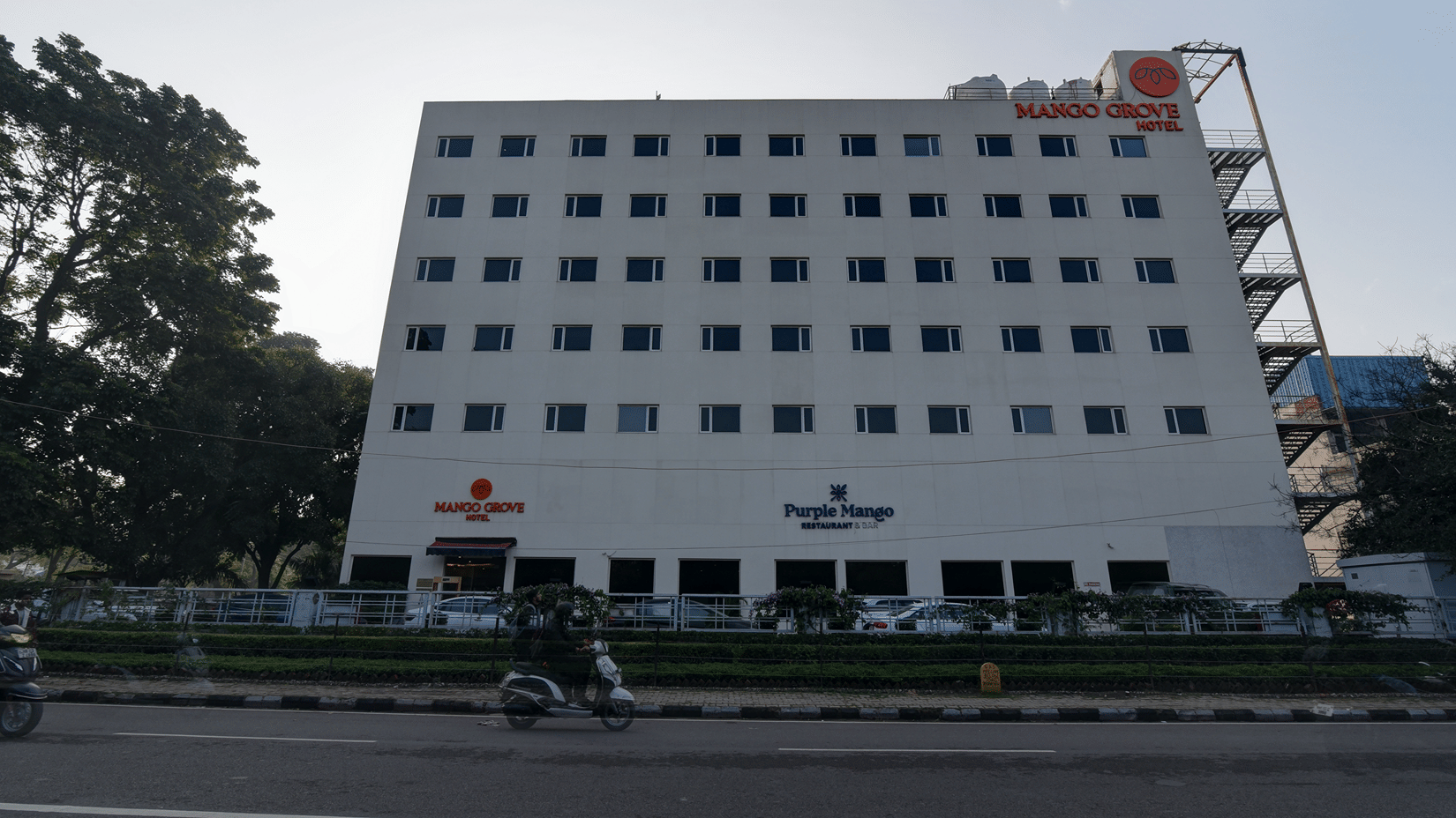 Hotel exterior with signage captured at dusk at Mango Grove Hotel.