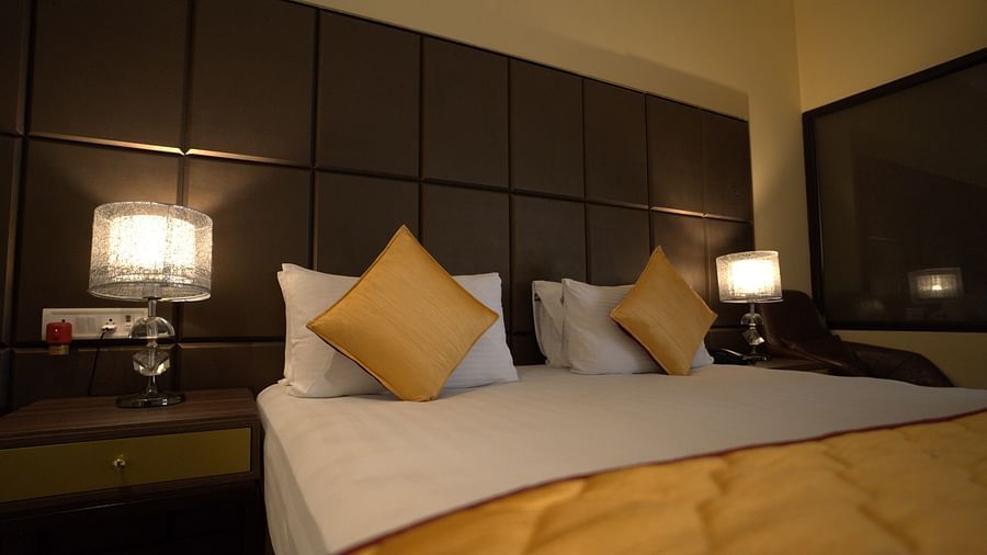 Deluxe Garden View Room at Citrus Classic Resorts and Spa Mahabalipuram ECR featuring a plush bed with fresh linen and pillows with cushions and lamps lit on both sides
