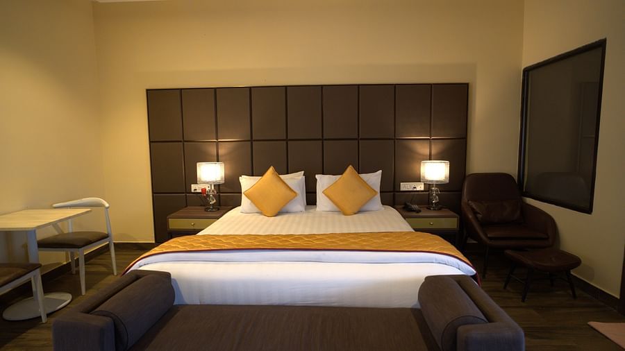 Warmly lit Junior Suite at Citrus Classic Resorts and Spa Mahabalipuram ECR featuring a plush bed with a divan at its foot and two sitting spaces on both sides