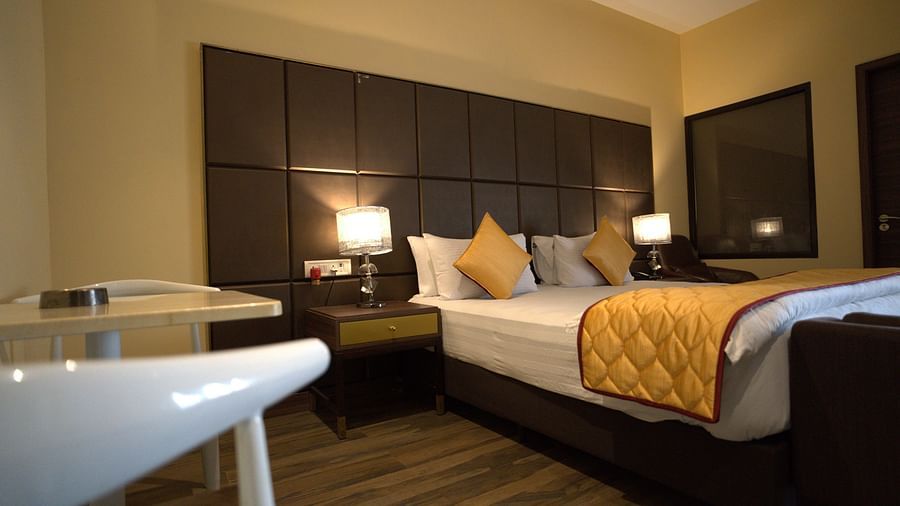 Premium Room at Citrus Classic Resorts and Spa Mahabalipuram ECR featuring the handrest of the chair and a plush bed with warmly lit lamps on both sides