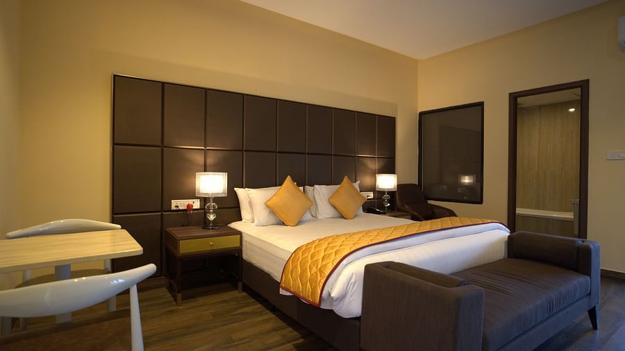 Premium Room at Citrus Classic Resorts and Spa Mahabalipuram ECR featuring a plush bed with a divan at its foot next to which the door to the bathroom is open