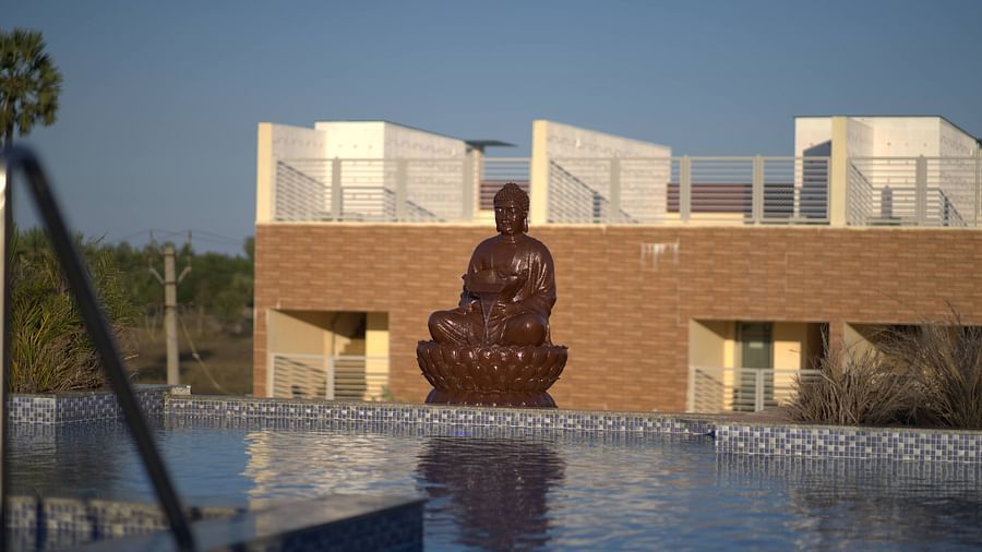 Swimming pool at Citrus Classic Resorts and Spa Mahabalipuram ECR featuring a statue of Buddha at the deck with its reflection on the water getting blurred