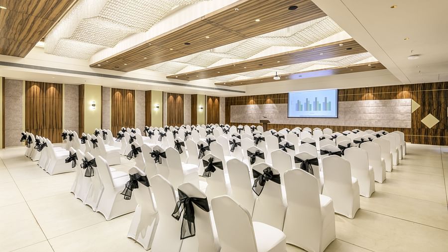 Elegant banquet hall at the Golden Tulip, Candolim, Goa, arranged with white chairs and a presentation screen.