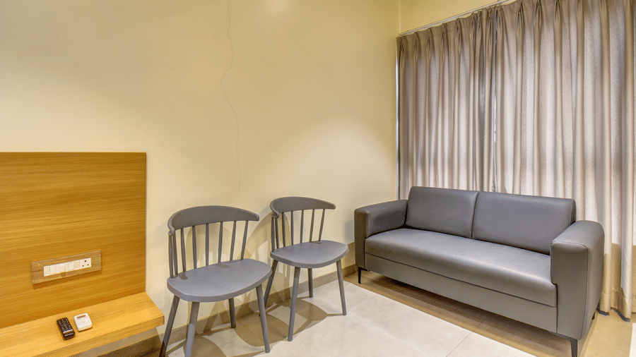 Seating area with sofa, chairs, side table, and curtained window at VITS Select Nashik Hotels & Resorts.