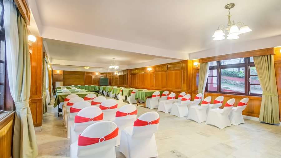 Image of a banquet hall with chiars and a chandelier hanging from the ceiling Image of  a dining space with neatly arranged chairs and tables at Summit Tashi Ghang Heritage Resort, Pelling