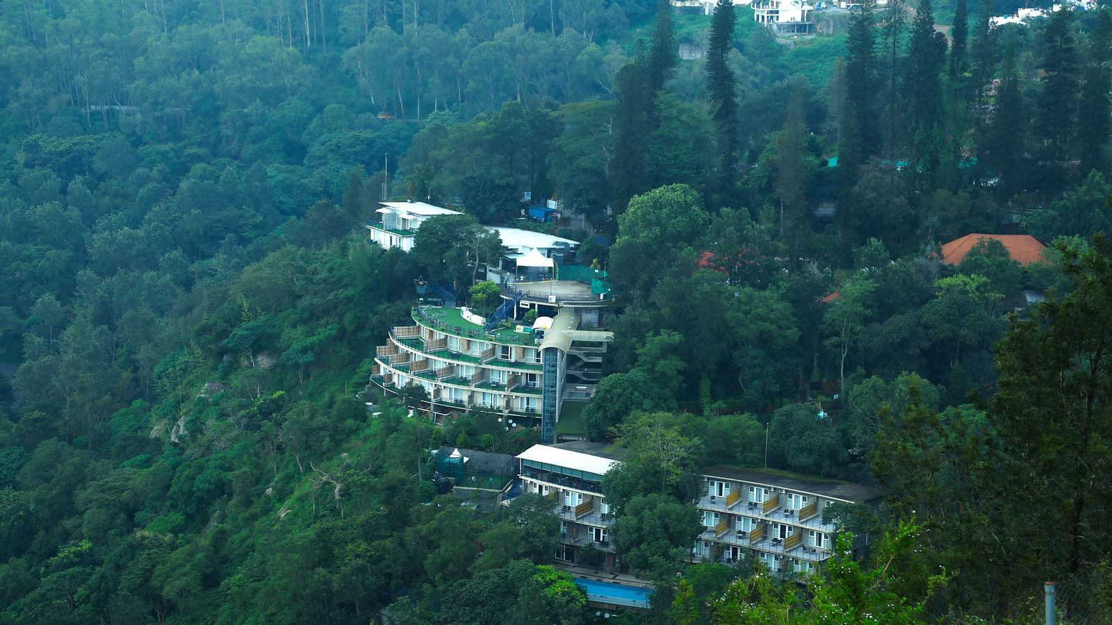 Drone shot of the hotel surrounded by the mountains and lush greenery - Great Trails Yercaud by GRT Hotels